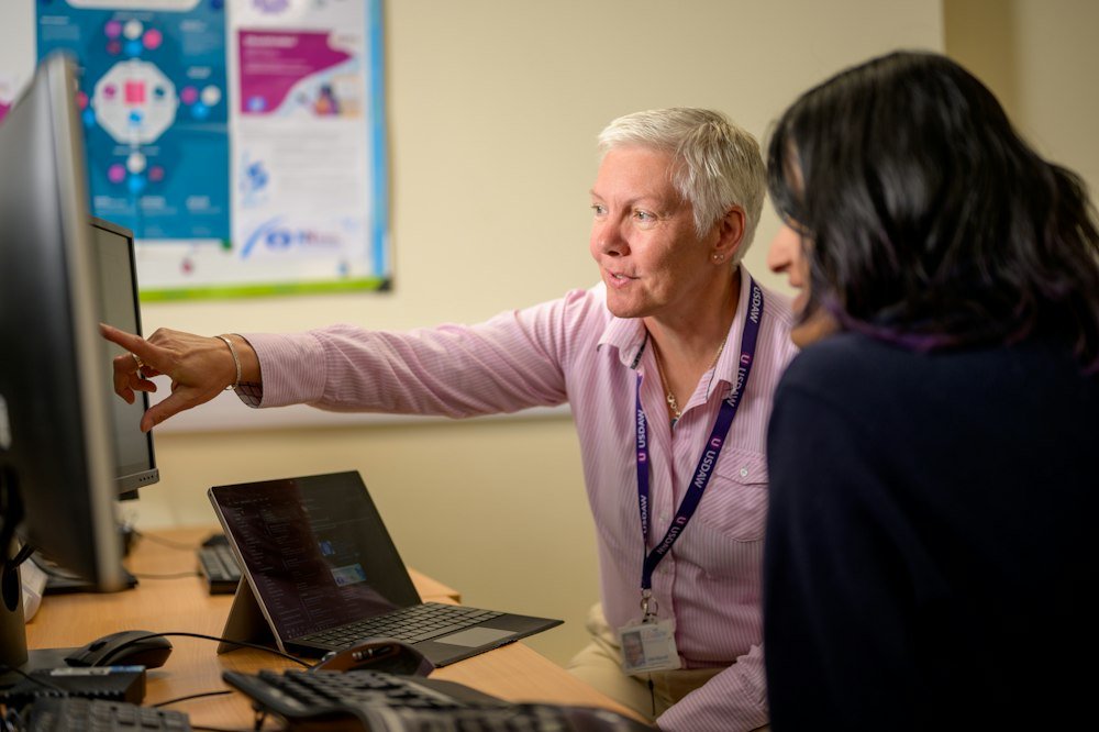 Colleagues discussing IT support requirements at a computer