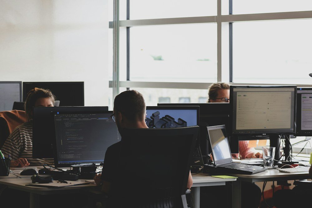 IT support professionals working together at computer monitors in a modern office
